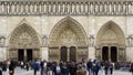 Tourists walking near Notre-Dame western facade, gothic architecture, Paris