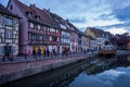 Colmar, France - April 30, 2017: Tourists walking by the canal and colourful houses after sunset in Colmar