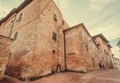 Tourists walking past historical brick houses of traditional Tuscan town