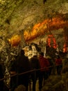 Tourists walking on path among the illuminated stalactites and stalagmites