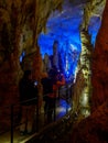 Tourists walking on path among the illuminated stalactites and stalagmites