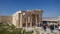 Tourists walking through the propylaea of the Acropolis of Athens on a sunny day in spring with the city landscape and a Royalty Free Stock Photo