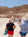 Tourists walking towards a tomb carved on the side of a mountain near Abu Simbel in Egypt