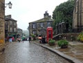 Tourists walking with umbrellas on a rainy day in the center of Howarth in West Yorkshire a historic village famous for the bronte