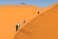 Tourists walking up a red dune in Sossuslvei, Namib Naukluft National Park, Namib desert, Namibia Royalty Free Stock Photo