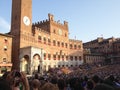 Tourists watching the colorful and fancy traditional costume parades at the horse race, Palio di Siena, held in medieval square Royalty Free Stock Photo