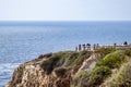 Tourists wearing face masks standing on a cliff overlooking the ocean