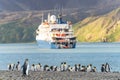 Tourists in zodiacs of an Antarctic expedition ship disembarking in Fortuna Bay on South Georgia, king penguins in the foreground.