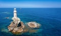 The Tourlitis lighthouse on a steep rock in calm, blue sea
