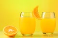 Tow glass with orange juice, half of an orange next to the glass