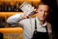 Barman pours alcoholic cocktail with ice using strainer and glass Royalty Free Stock Photo