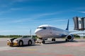 Tow tractor pushes the passenger airliner away from the jet bridge Royalty Free Stock Photo