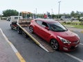 A tow truck car transporter, lorry carrying a car for repairing at the city street