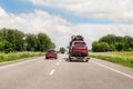 Tow truck trailer on highway carrying three damaged cars sold on insurance car auctions for repair and recovery. Vehicles