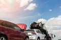 Tow truck trailer on highway carrying three damaged cars sold on insurance car auctions for repair and recovery. Vehicles