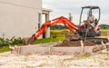 Towable Backhoe moving dirt into slab, wood form