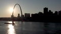 Towboat pushing barge loaded with corn grain down Mississippi River, passing St. Louis Gateway Arch