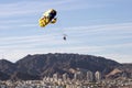 Towed parachute over city and mountainous backdrop