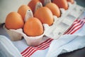 On a towel with red stripes is a cardboard box with a brown chicken eggs Royalty Free Stock Photo