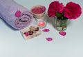 Towel, roses, pink sea salt, handmade soap, pink candle and rose petals on a gray background. Royalty Free Stock Photo