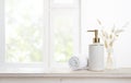 Towel and soap dispenser on table against blurred window background Royalty Free Stock Photo