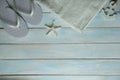 Towel, starfish, anchor, white beach flip flops on light blue wooden background, summer time concept, vacation time, travel, beach