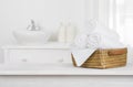 Towels basket on wooden table top with blurred bathroom interior