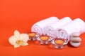 Towels, candles and orchid flowers for a spa relaxation on orange background Royalty Free Stock Photo