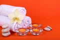 Towels, candles and orchid flowers for a spa relaxation on orange background Royalty Free Stock Photo