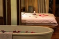 Towels, flowers and red rose petals decorations on the bed, flowers and petals in bathtub, concept of Honeymoon