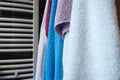 Towels hang next to a heated towel rail, wall radiator or radiator. White, blue, pink, red towels. Organization of