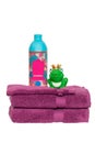 Towels isolated. Closeup of a stack or pile of violet soft terry bath towels with a wash softener and a funny green king frog Royalty Free Stock Photo