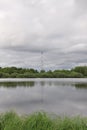 metal cell tower on the shore of a pond outside the city in the wilderness Royalty Free Stock Photo