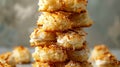 A tower of bitesized coconut macaroons drizzled with a coconut cream frosting and sprinkled with toasted coconut flakes