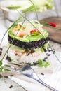 Tower of black and white rice with shrimp and zucchini