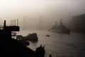 Tower Bridge, London, in a dense fog with a military battleship in front Royalty Free Stock Photo