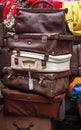 Tower of old brown leather suitcases, travel bags squashed onto of each other