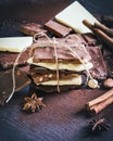 A tower of chocolate bars wrapped like a chocolate present . Various chocolate pieces, spices,cocoa powder and nuts over dark wood Royalty Free Stock Photo