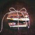 A tower of chocolate bars wrapped like a chocolate present . Various chocolate pieces over dark wood background.