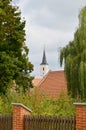 The tower of the church seen from afar between the trees