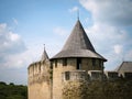 Tower with a conical roof and merlons of a medieval castle against a blue sky Royalty Free Stock Photo