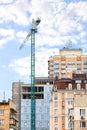 Tower crane against the background of a modern multi-storey residential building under construction and a blue cloudy sky Royalty Free Stock Photo