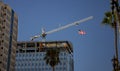 Tower Crane with an American flag near a modern office building under construction against a blue sky Royalty Free Stock Photo