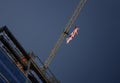 Tower Crane with an American flag near a modern office building under construction against a blue sky Royalty Free Stock Photo