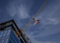 Tower Crane with an American flag waving near a modern office building under construction against a cloudy sky Royalty Free Stock Photo