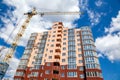 Tower crane building modern apartment house on a background of blue cloudy sky at sunny day. Real estate concept