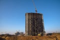 Tower crane constructing a new building at construction site on the background blue sky. Excavator digs the ground Royalty Free Stock Photo