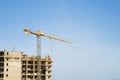 Tower crane constructing a new residential building at a construction site against blue sky. Renovation program Royalty Free Stock Photo