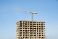Tower crane constructing a new residential building at a construction site against blue sky. Renovation program Royalty Free Stock Photo