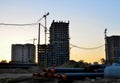 Tower crane constructing a new residential building at a construction site at sunset background. Royalty Free Stock Photo